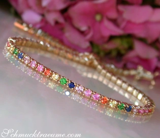 Gelbgold-Armband mit farbenfrohen Saphiren, Detailaufnahme, Rosen im Hintergrund