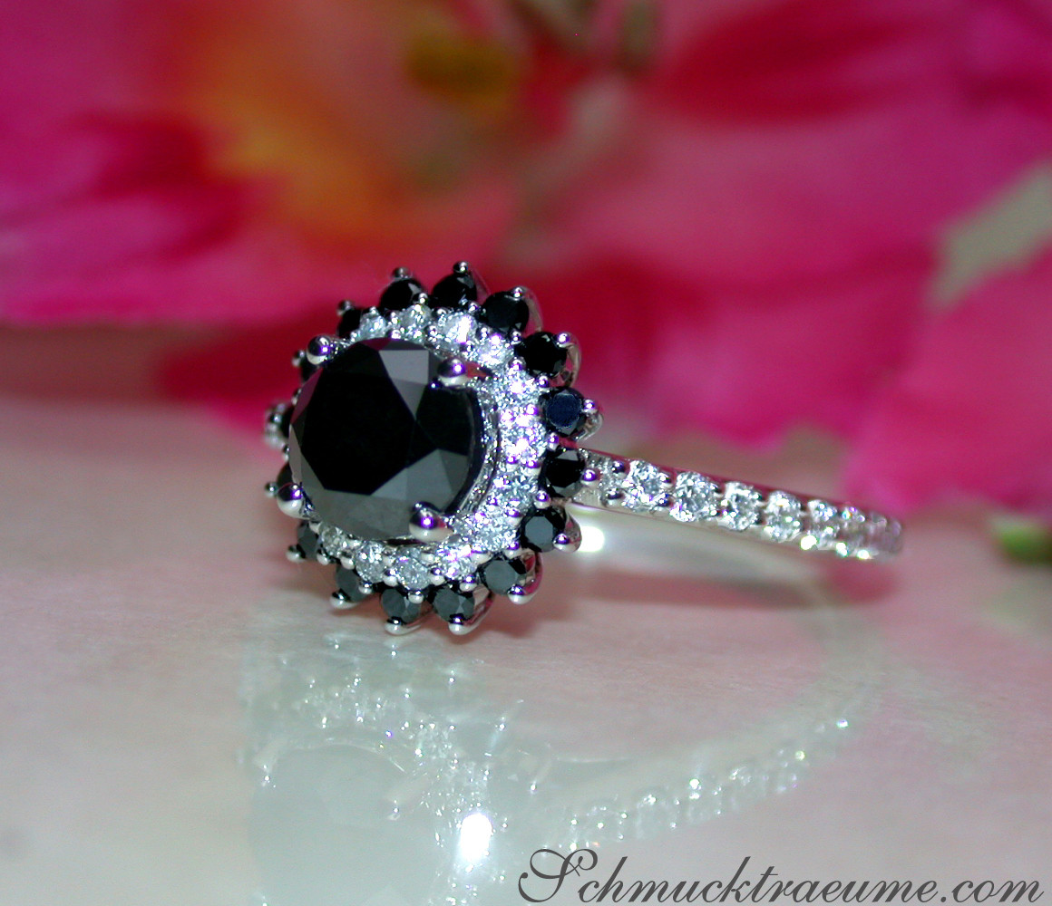 Schwarzer Diamant Solitär-Ring in Weißgold, Detailaufnahme mit Blume im Hintergrund