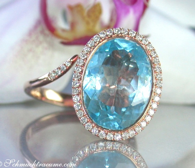 Blautopas-Ring mit Diamant-Halo, roségoldene Verarbeitung, elegante Detailaufnahme Blautopas-Ring mit Diamant-Halo, roségoldene Verarbeitung, elegante Detailaufnahme