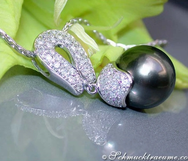 Tahitiperlen-Anhänger mit Diamanten, detailreich verarbeitet, auf grünem Blatt liegend. Tahitiperlen-Anhänger mit Diamanten, detailreich verarbeitet, auf grünem Blatt liegend.
