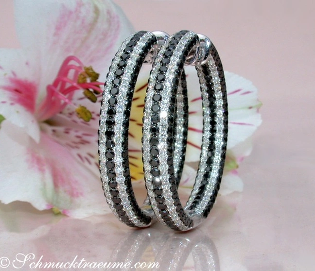 Schwarze und weiße Diamant-Creolen auf Blüte, Detailaufnahme Schwarze und weiße Diamant-Creolen auf Blüte, Detailaufnahme