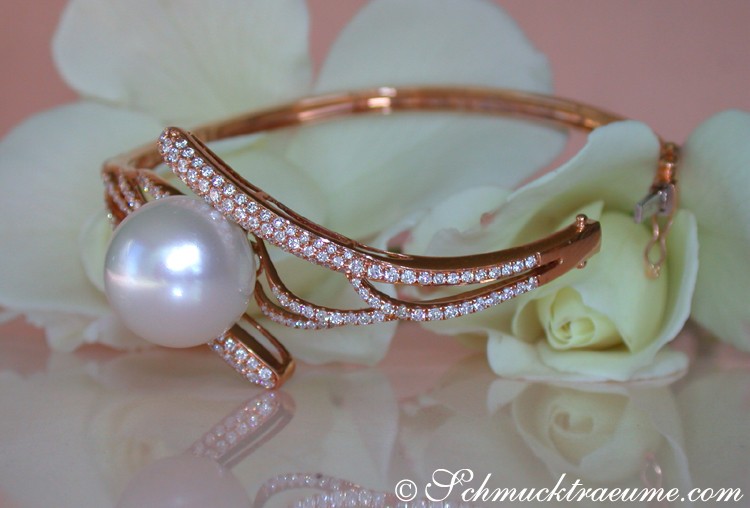 Goldarmreif mit Südseeperle und Diamanten, Detailaufnahme, Rosenblüte im Hintergrund