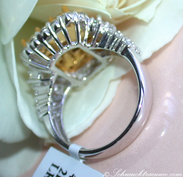 Detailansicht eines gelb-diamantenbesetzten Rings in Weißgold, umgeben von Rosenblättern