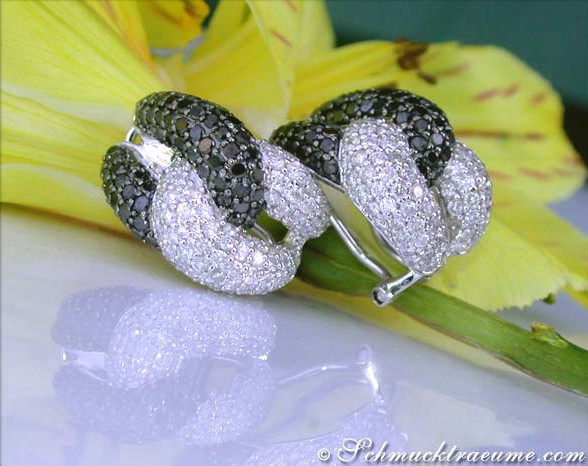 Extravagante Ohrringe mit schwarzen und weißen Diamanten auf Blume gelegt