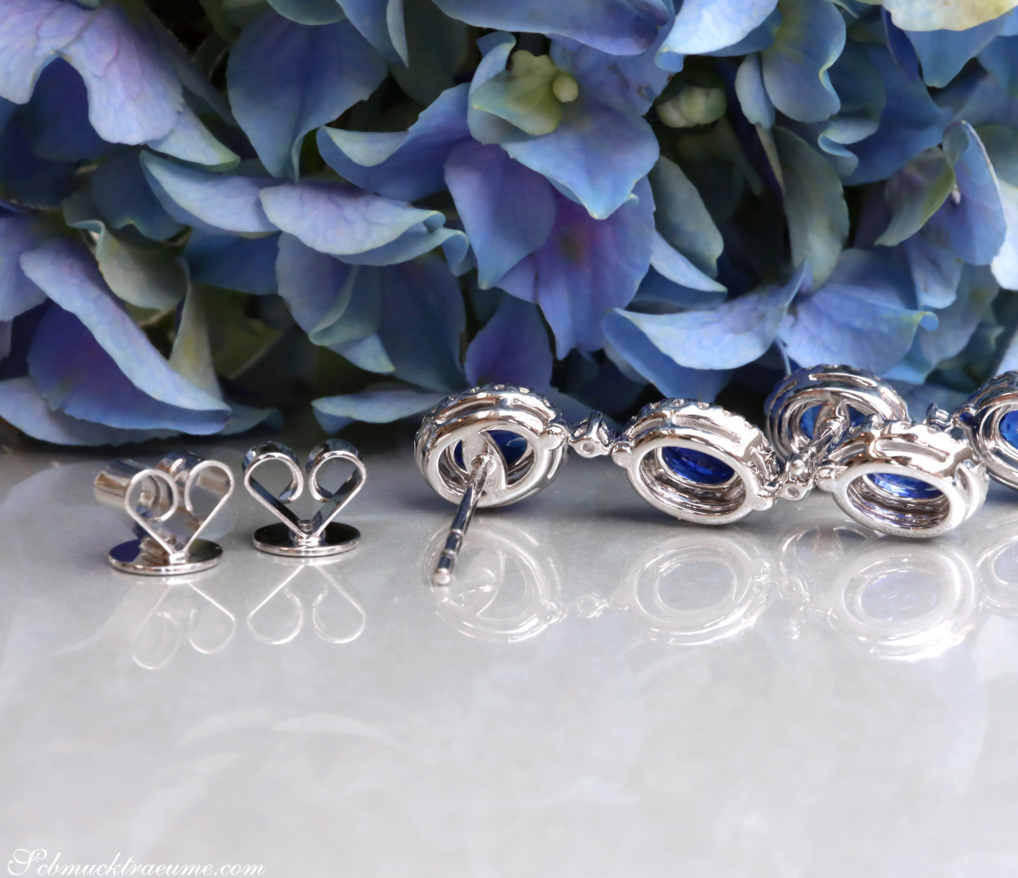 Saphir-Ohrgehänge mit Brillanten auf Marmor vor Blütenblättern