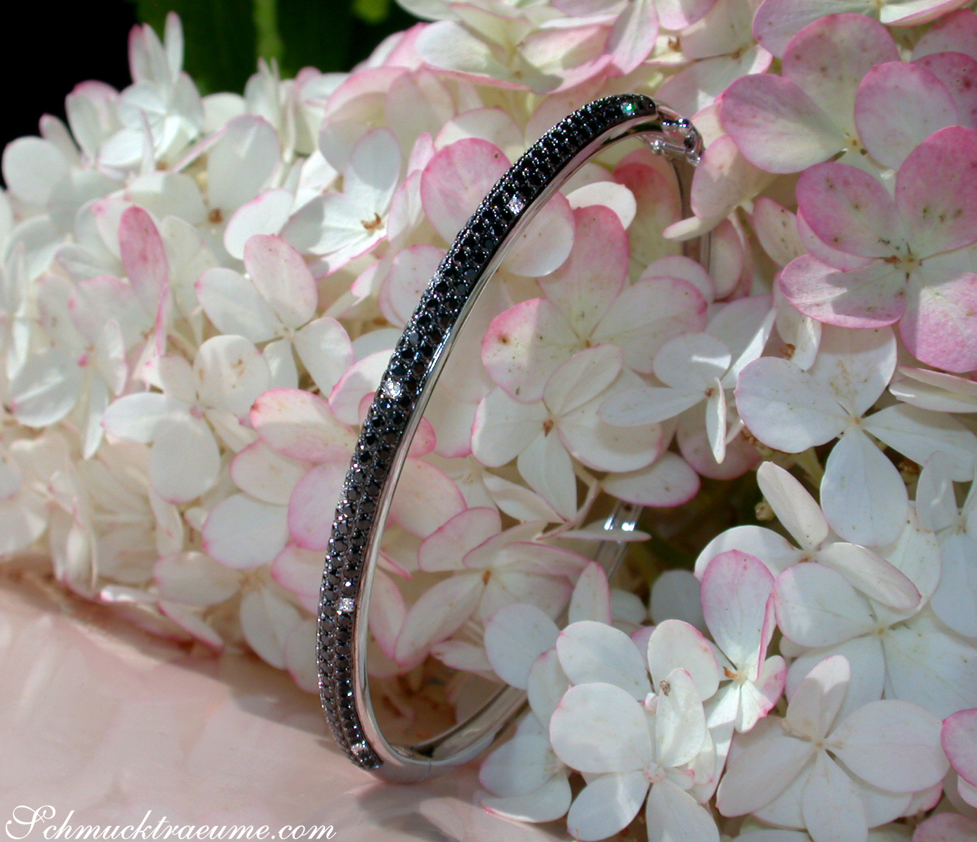 Blumenhintergrund mit feinem Armreif aus Weißgold 585, schwarz-weiße Diamanten, Detailaufnahme