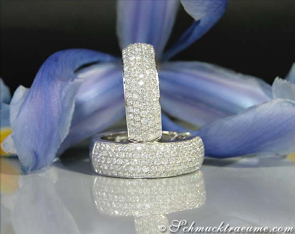 Opulente Brillanten Pavé Creolen in Weißgold: Detailansicht mit blauen Blüten im Hintergrund