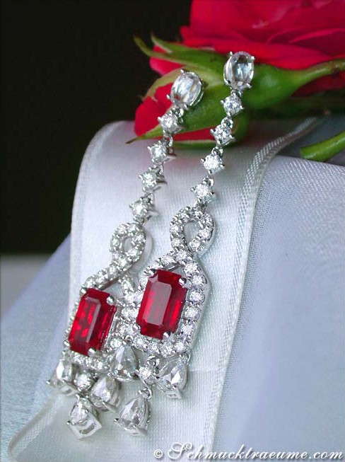 Rubin-Ohrgehänge mit Diamanten auf weißem Tuch mit Rosenblüte