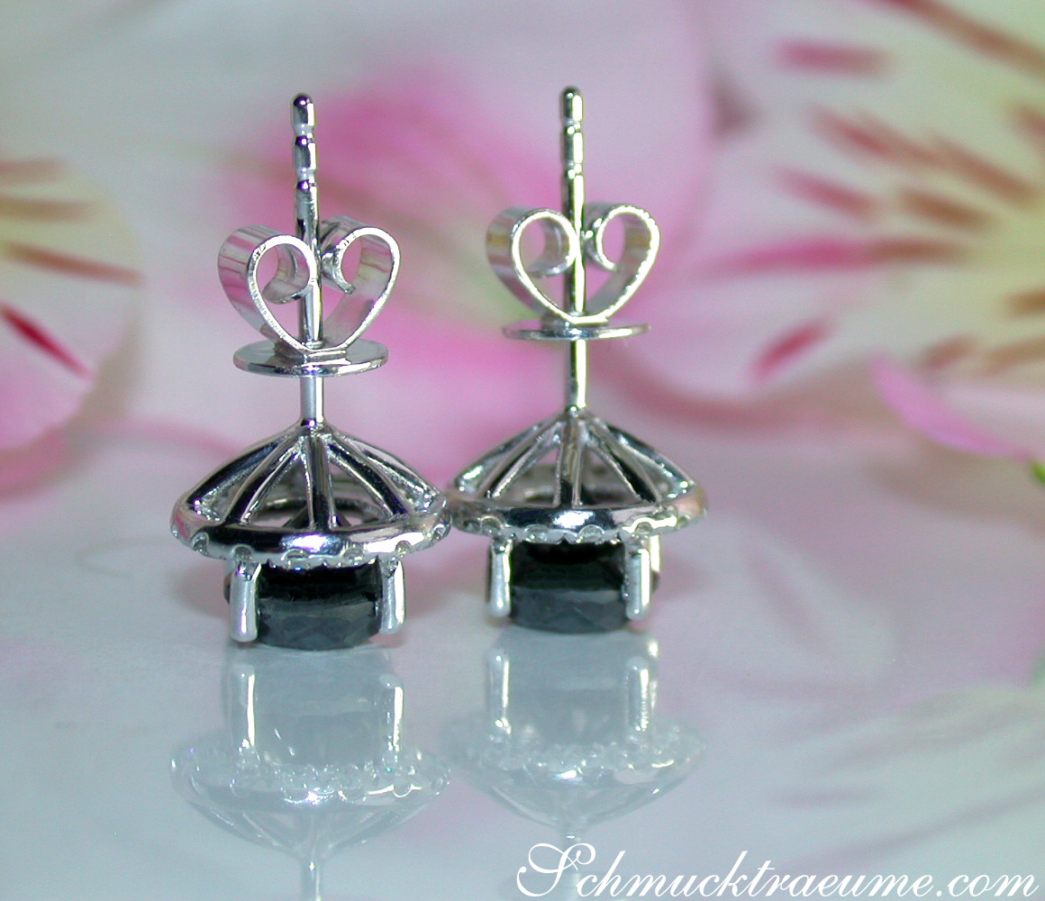 Silberne Herz-Ohrstecker mit schwarzen Diamanten auf weißem Hintergrund