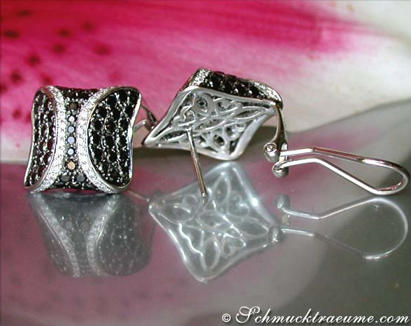 Silberne Ohrstecker mit schwarzen und weißen Diamanten, Detailaufnahme, schlichte Form, reflektierender Untergrund