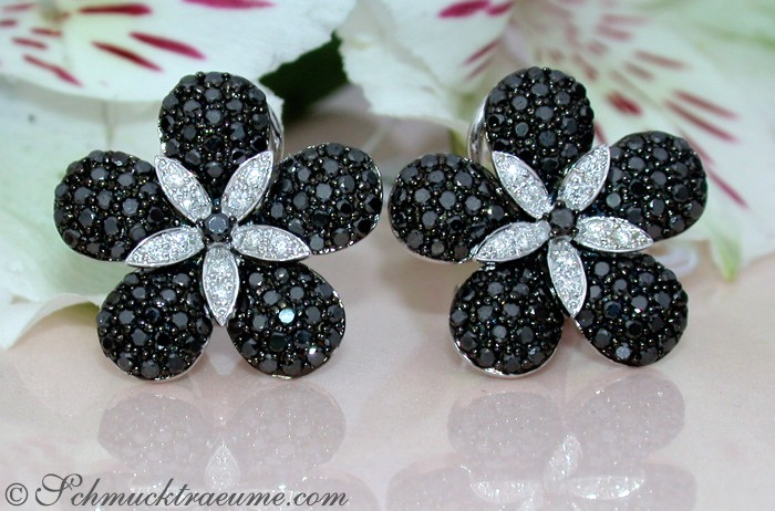 Schwarze Diamant-Blumenohrringe auf weißem Hintergrund mit Blütenmotiv.