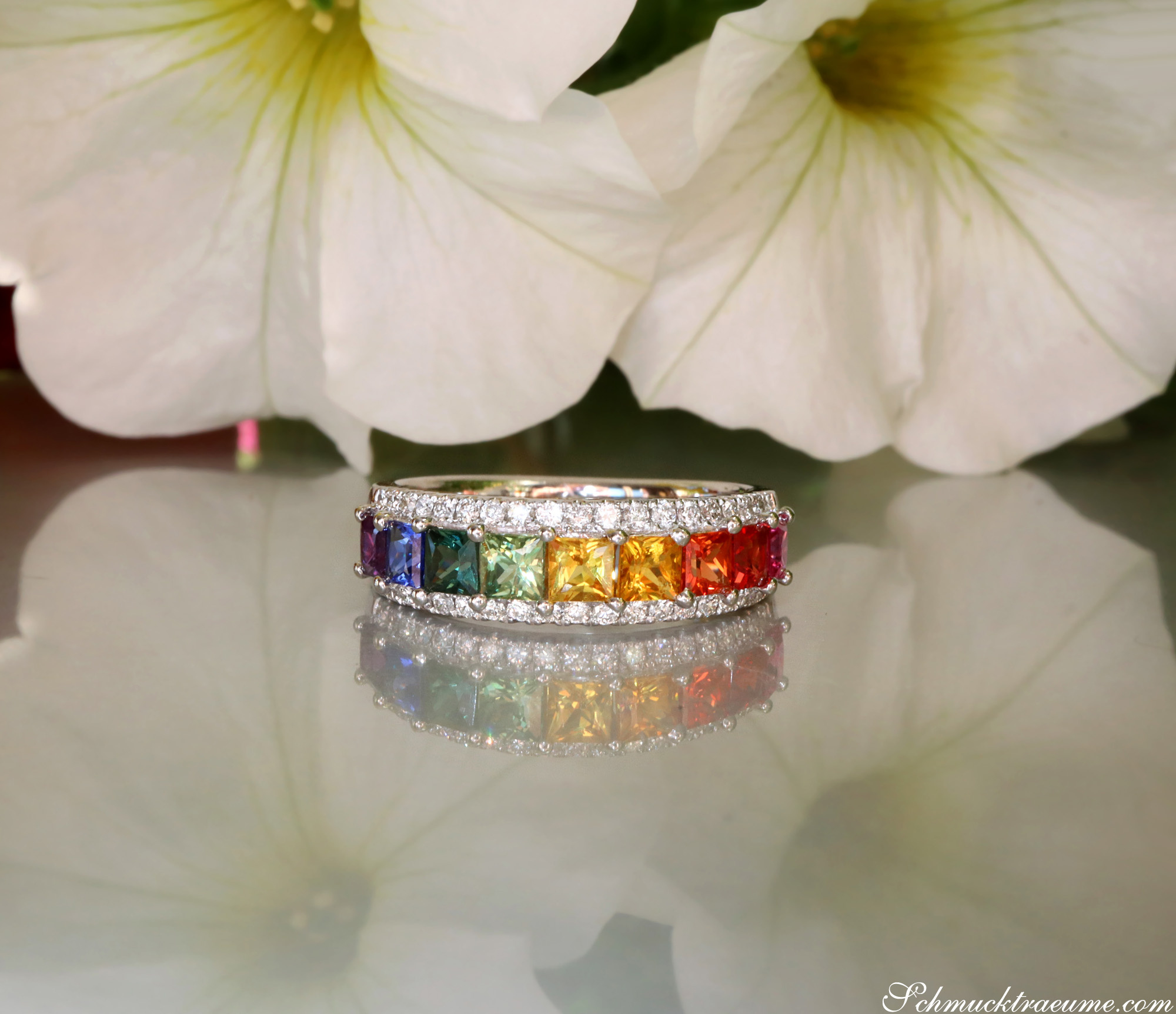 Weißgold-Ring mit Regenbogen-Saphiren und Brillanten, Blütenhintergrund.