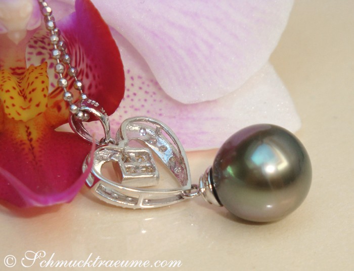 Weißgold-Anhänger mit Herz-Diamanten und Perle, detailreich, vor Orchidee.
