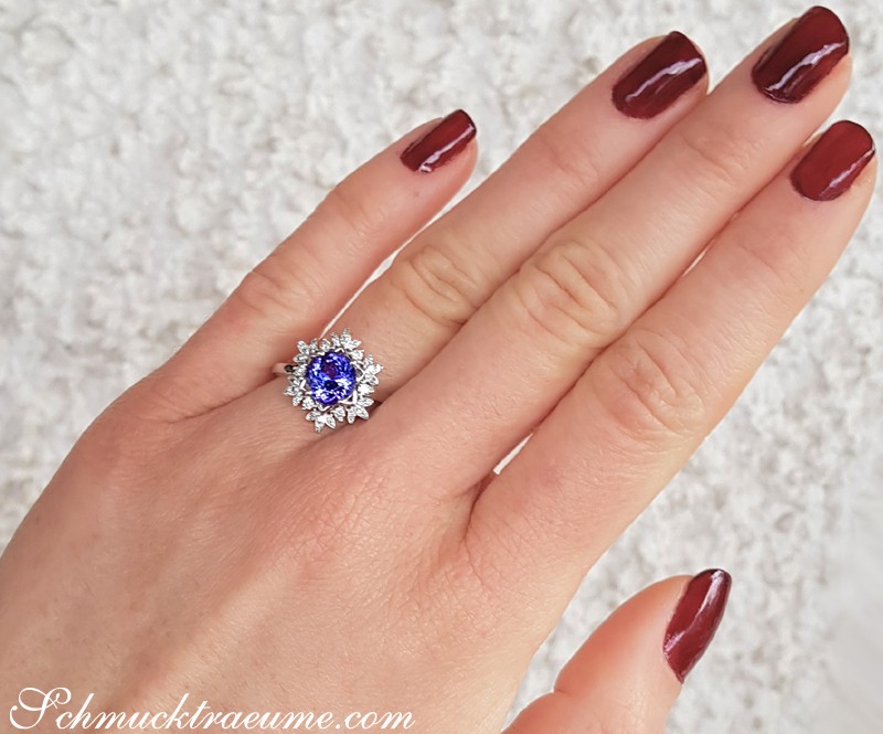 Finger mit dunkelrotem Nagellack, Tansanit-Ring mit Diamanten im Schneeflocken-Design, Weißgold 750