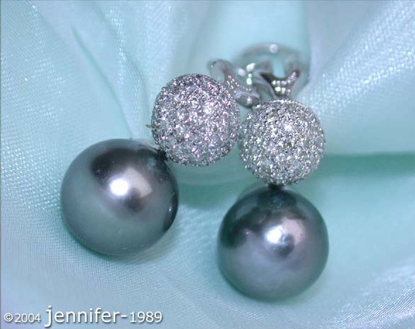 Tahitiperlen-Ohrstecker mit Brillanten-Pavé in Weißgold 750, Detailaufnahme auf blauem Hintergrund.