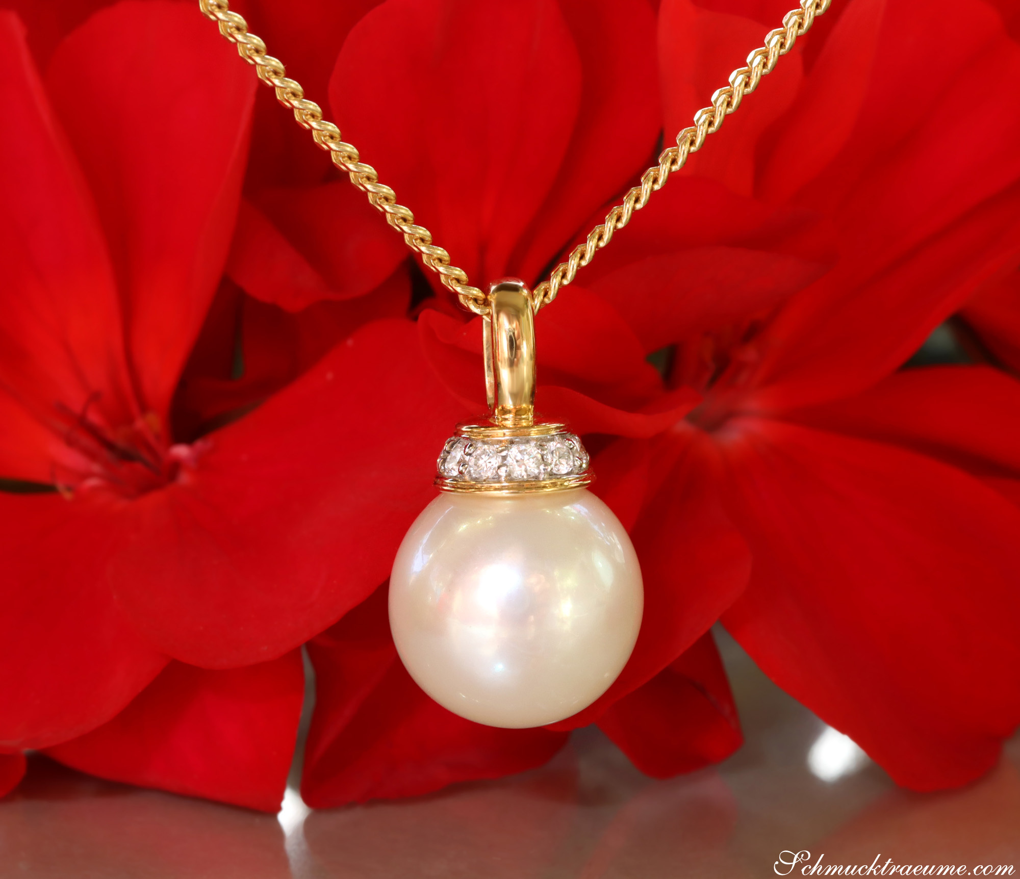 Goldkette mit Süßwasserperlenanhänger und Brillanten vor rotem Blütenhintergrund