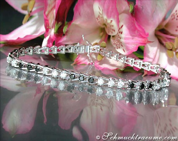 Schwarz-Weiß-Diamant-Tennisarmband auf rosa Blütenhintergrund