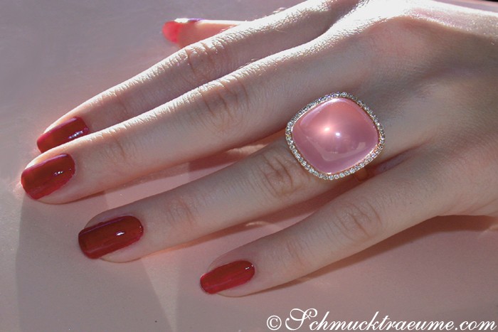 Rosenquarz-Ring mit Diamanten in Roségold, detailreich, modern, Nagellack rot, Händedesign, Sonnenlicht.