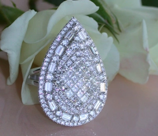 Diamant-Tropfen-Ring in Weißgold 750, detailliert mit Diamanten, vor Rosenblüte.