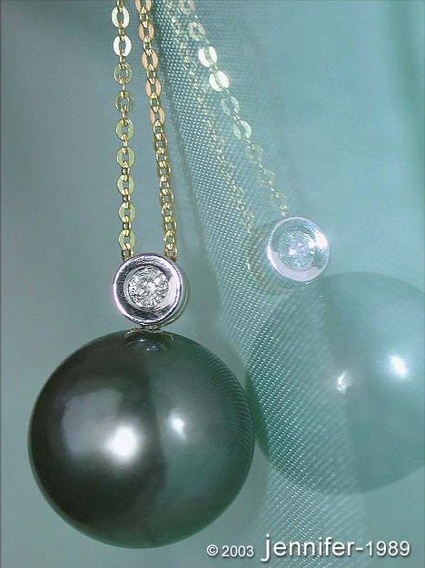 Gelbgoldanhänger mit Tahitiperle und Brillant, Detailaufnahme, Hintergrund aus Netzmaterial.