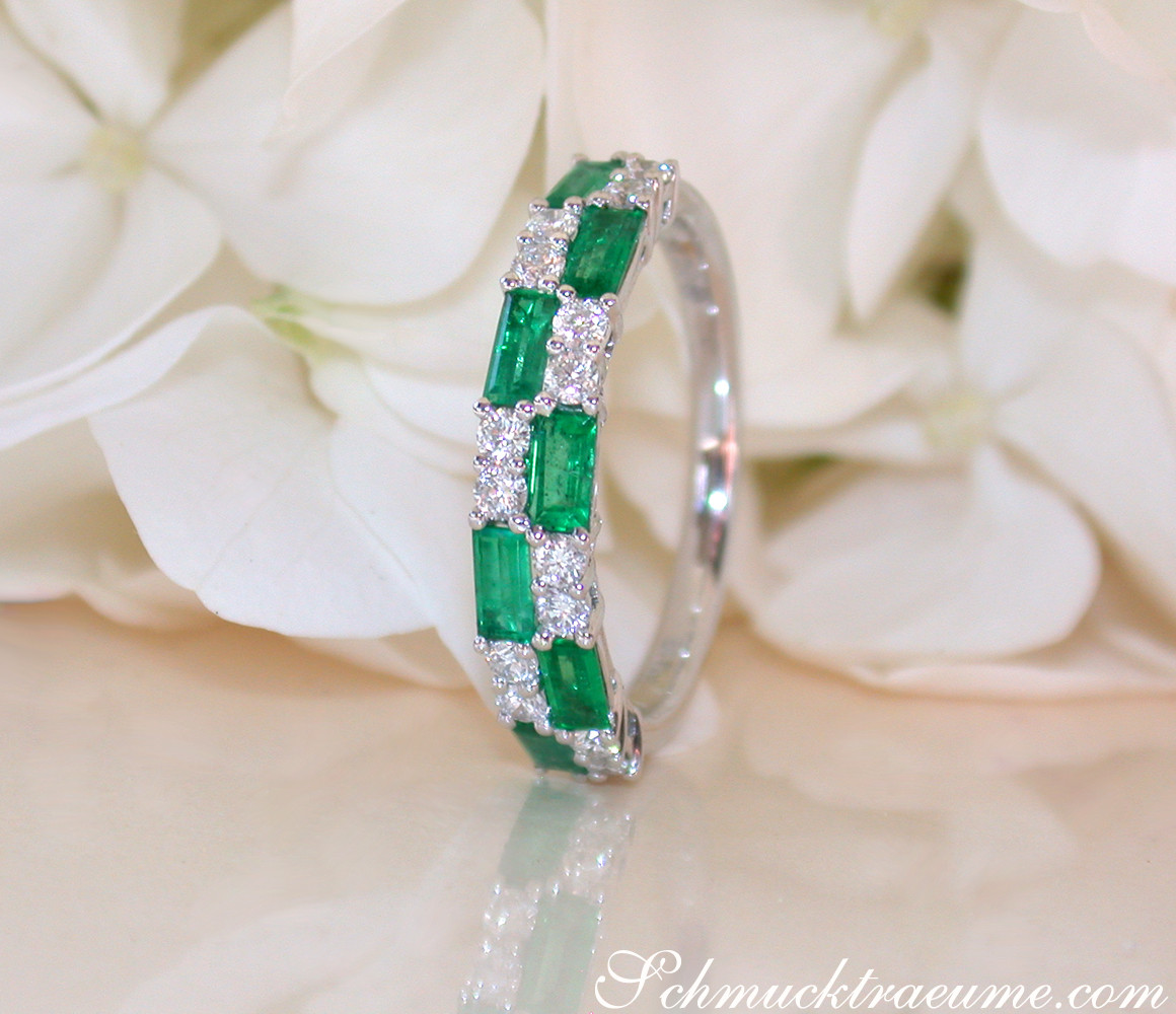 Smaragd- und Diamant-Bandring mit Baguette-Schliff auf weißem Blütenhintergrund