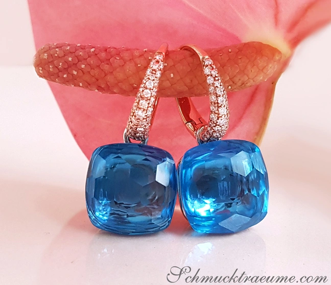 Blautopas-Ohrringe mit Diamanten, roségoldene Hülse, Blüte im Hintergrund Blautopas-Ohrringe mit Diamanten, roségoldene Hülse, Blüte im Hintergrund