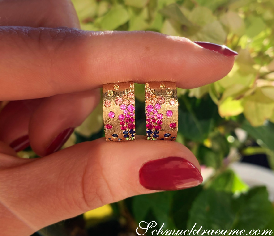 Gelbgold 585 Ohrringe mit farbigen Saphiren und Rubinen, Detailaufnahme vor grünem Hintergrund.