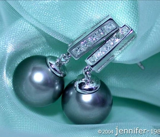 Tahitiperlen-Ohrringe mit Diamanten in Weißgold 750, Detailaufnahme auf grünem Stoff.
