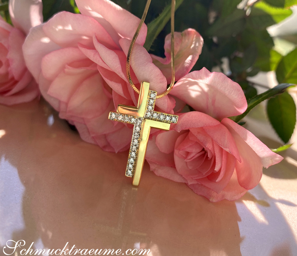Goldener Kreuzanhänger mit Diamanten, umgeben von rosa Rosenblüten