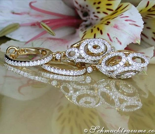 Gelbgold-Brillanten-Ohrgehänge mit filigranem Design auf Blütenhintergrund