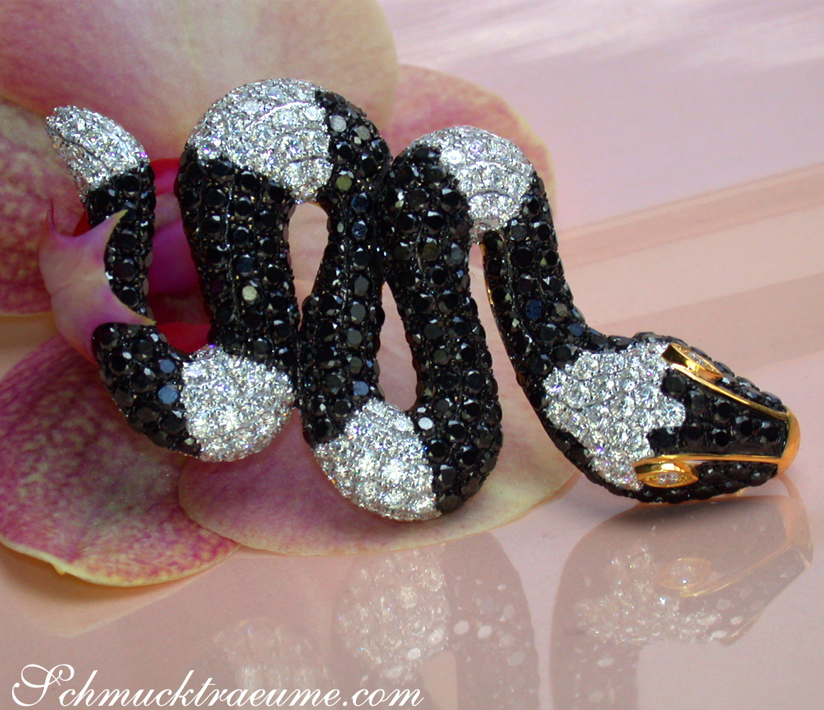 Schlangenanhänger mit schwarzen und weißen Diamanten auf Orchideenblüte.