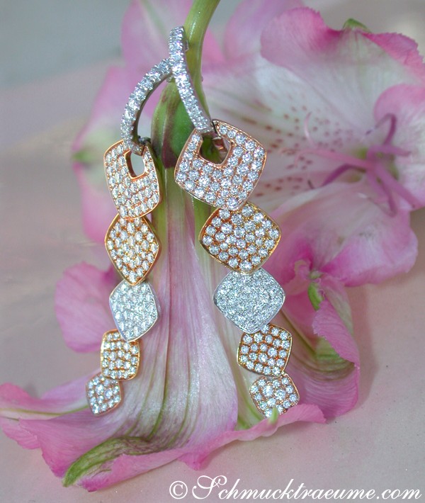 Diamant-Ohrgehänge mit weißem Gold und Rosenblüte im Hintergrund