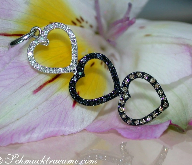 Herz-Anhänger aus Weißgold mit Diamanten in Weiß, Schwarz und Braun, auf Blütenblatt dargestellt Herz-Anhänger aus Weißgold mit Diamanten in Weiß, Schwarz und Braun, auf Blütenblatt dargestellt