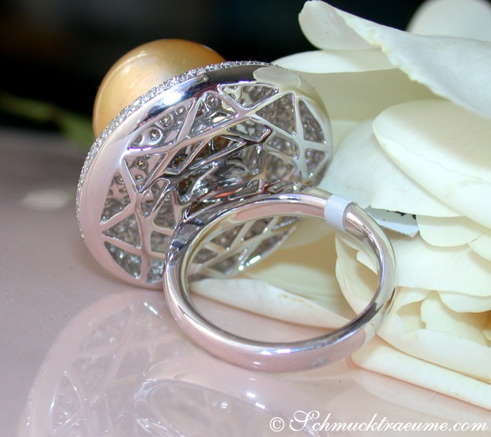 Goldener Ring mit Perle und Diamanten, Detailaufnahme auf weißer Blume