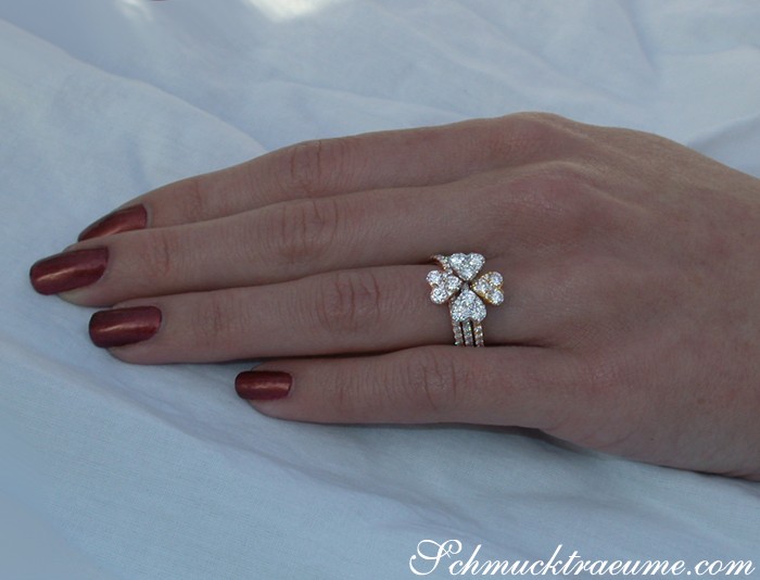 Goldener Herzring mit drei Brillanten auf Hand mit lackierten Nägeln