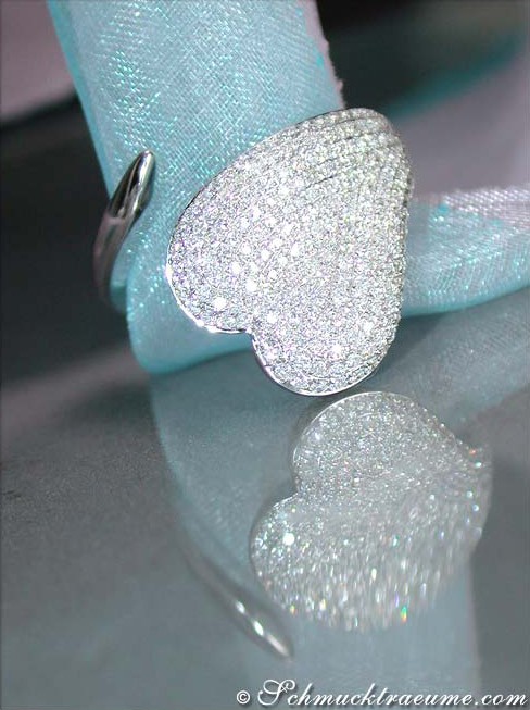 Herzformiger Brillantenring aus Weißgold, detailreich verziert, auf blauem Stoff getragen