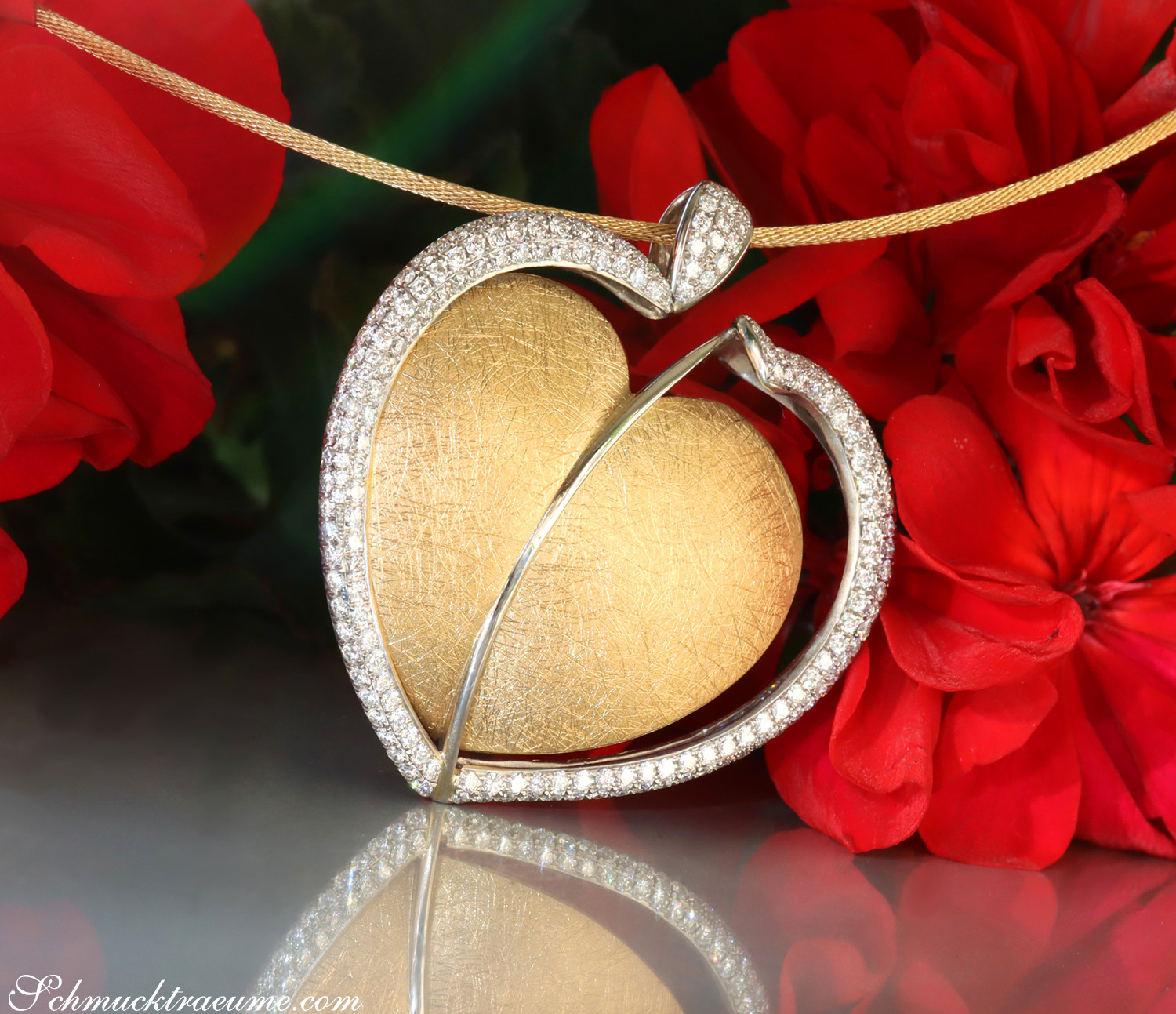 Herzform-Collier aus Gelbgold 750 mit Brillanten, Detailaufnahme, umgeben von roten Blüten.