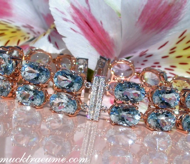 Goldene Aquamarin-Armband-Detailaufnahme mit Diamanten und Blütenhintergrund Goldene Aquamarin-Armband-Detailaufnahme mit Diamanten und Blütenhintergrund