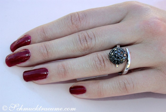 Schwarzer Diamantenkugelring auf Hand mit lackierten Fingernägeln