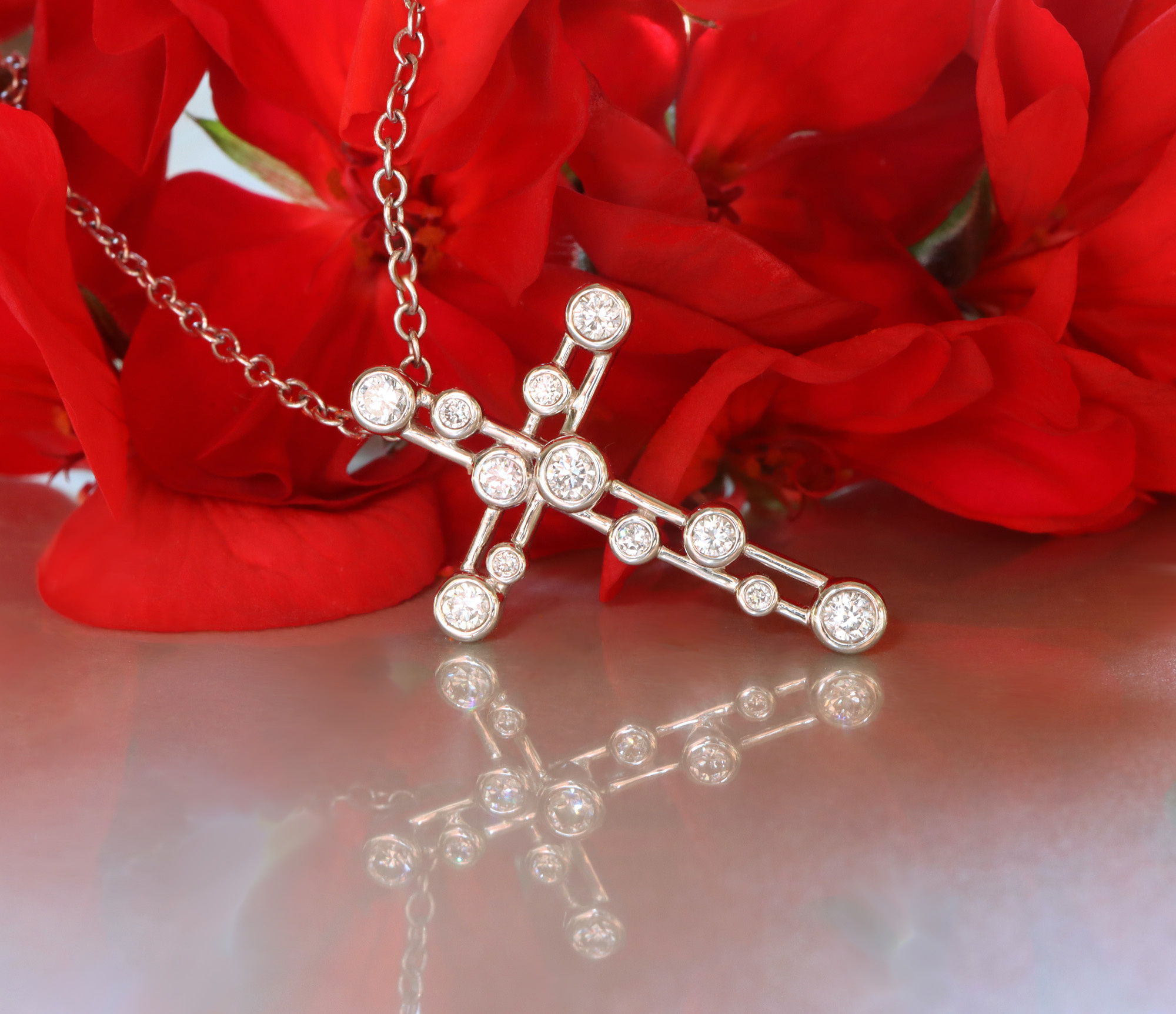 Raffinierter Diamantkreuzanhänger mit 0.400 Karat, Weißgold 750, vor roten Blüten.