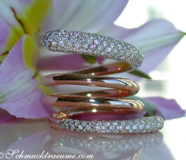 Glänzender mehrreihiger Diamantring in Roségold, spiralförmig gestapelt, vor Blüte. Glänzender mehrreihiger Diamantring in Roségold, spiralförmig gestapelt, vor Blüte.