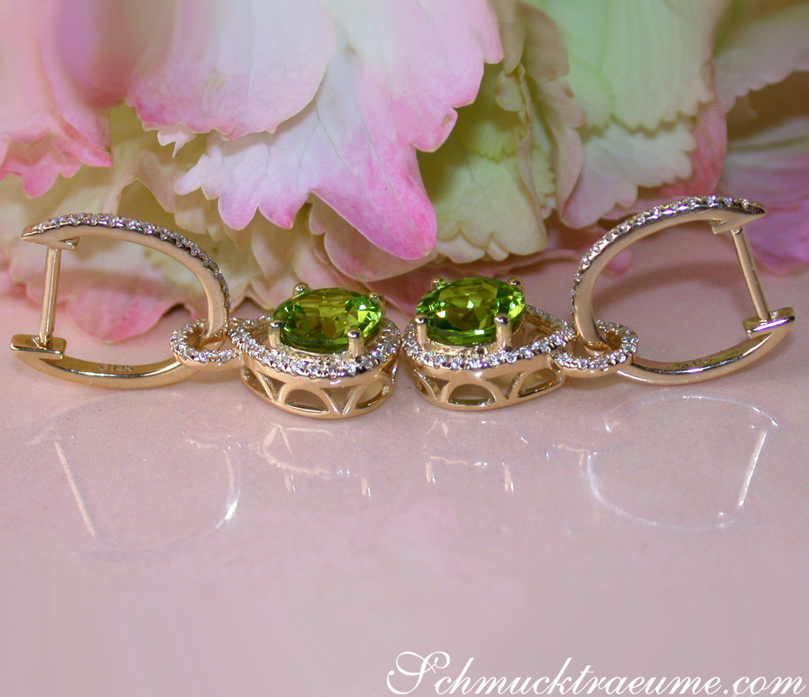 Peridot-Ohrringe mit Diamanten auf rosafarbenem Blütenhintergrund