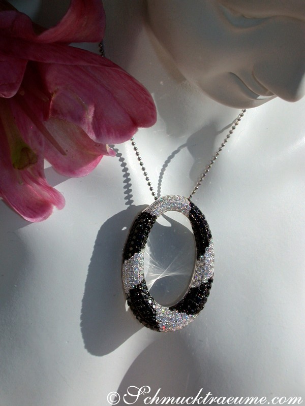 Schwarzer und weißer Diamant-Anhänger, oval, auf Halskette, neben Blume
