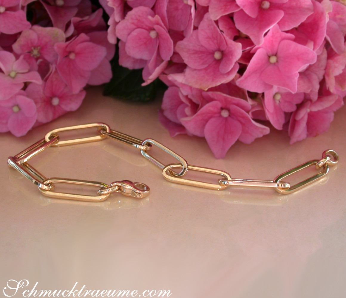 Gold-Papierklemm-Armband in Gelbgold 585 mit langen, luftigen Goldgliedern und klaren Linien, vor rosa Hortensienblüten.