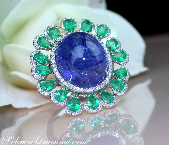 Weißgold-Tansanit-Ring mit Smaragden und Brillanten, Detailaufnahme, auf Rosenblüte liegend Weißgold-Tansanit-Ring mit Smaragden und Brillanten, Detailaufnahme, auf Rosenblüte liegend