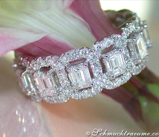 Weißgold-Diamantring mit Smaragdschliff und Brillanten, Detailaufnahme, auf Blume liegend.