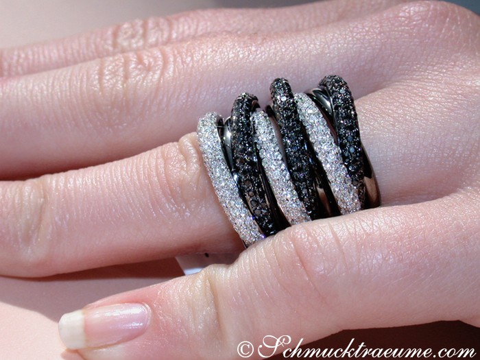 Mehreihiger Ring mit schwarzen und weißen Steinen, Detailaufnahme, Hand getragen.