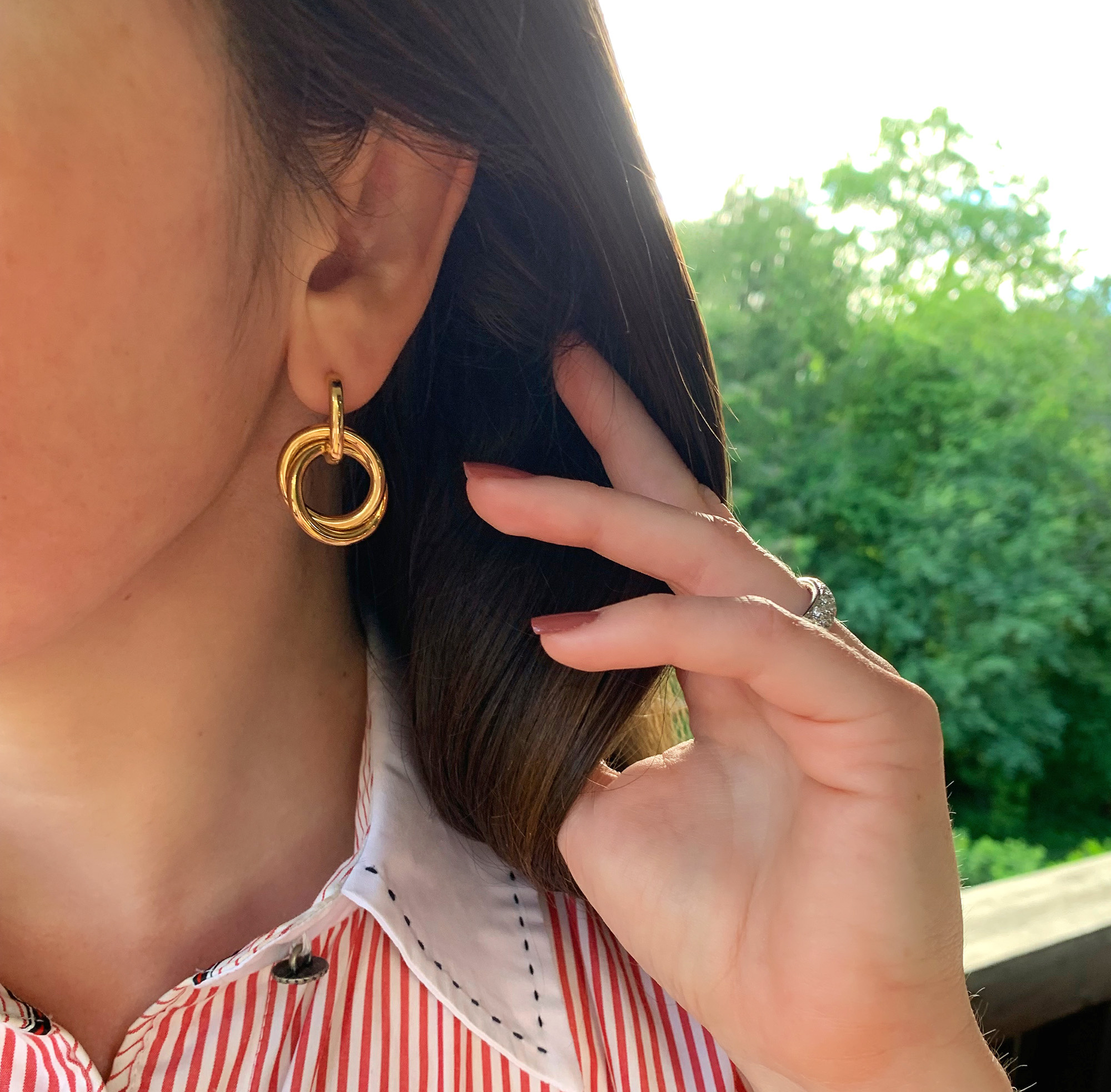 Goldene Ohrringe aus Gelbgold 585, Detailaufnahme vor grünem Hintergrund.