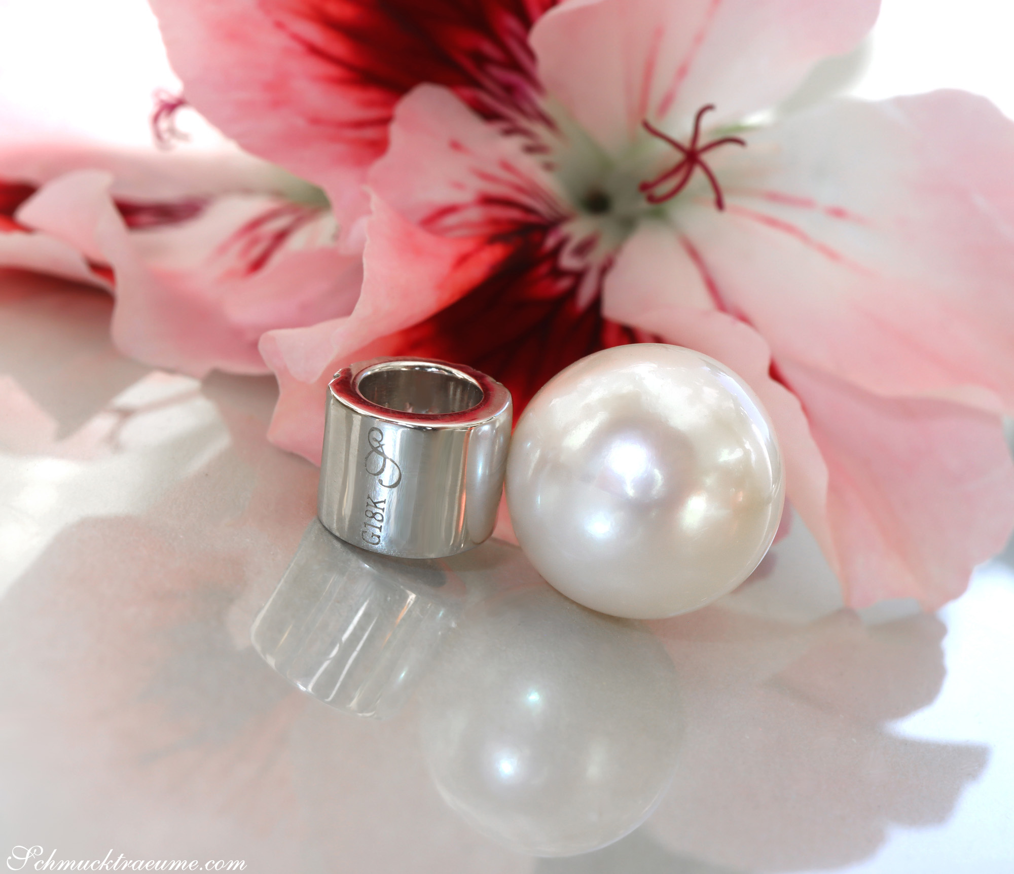 Perlenanhänger mit Baguette-Diamanten, Silberring, Blume im Hintergrund