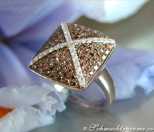 Silberner Ring mit braunen und weißen Diamanten, Detailaufnahme, Blüten im Hintergrund.